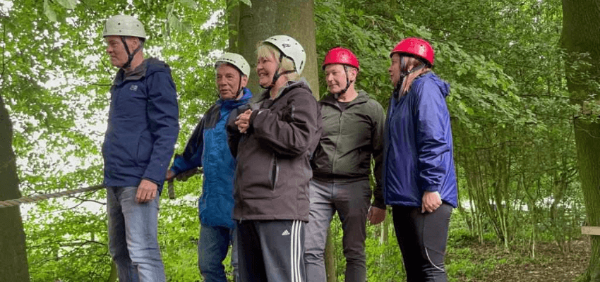 a group of people on a rope course in the woods during a networking meeting