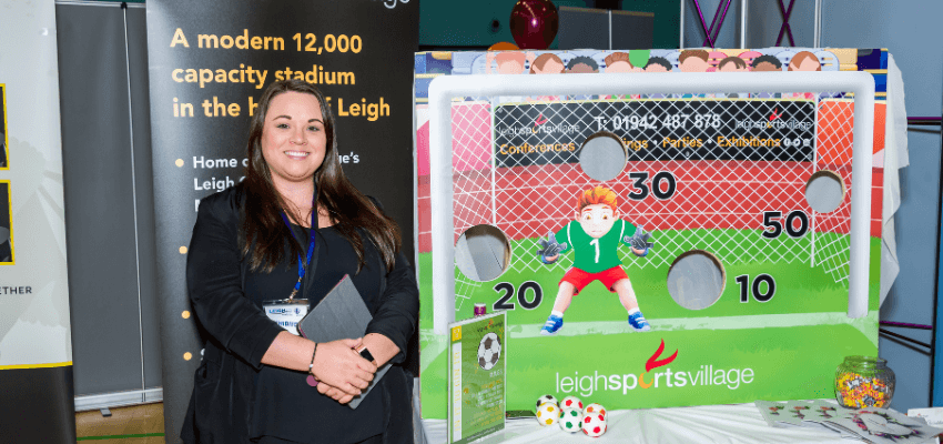 a person standing next to a table with a soccer game on it at a business expo